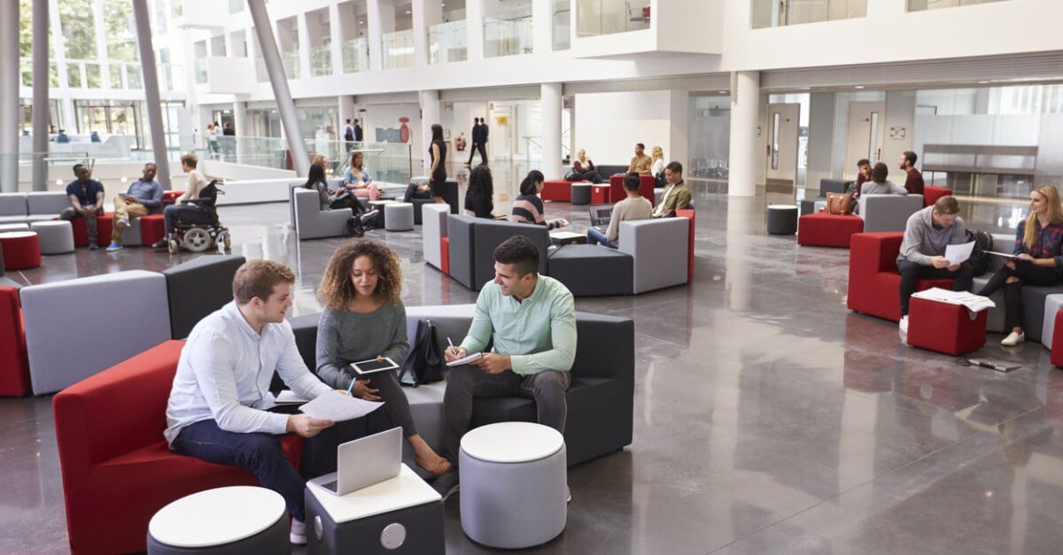 Allgemeine Infos zum Hotelmanagement Studium Viele Studenten sitzen in Foyer einer Hochschule